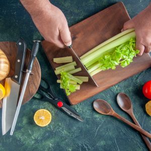 top-view-male-cook-cutting-celery-dark-table-salad-diet-meal-color-photo-food-health